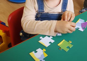 Dziewczynka układa puzzle.